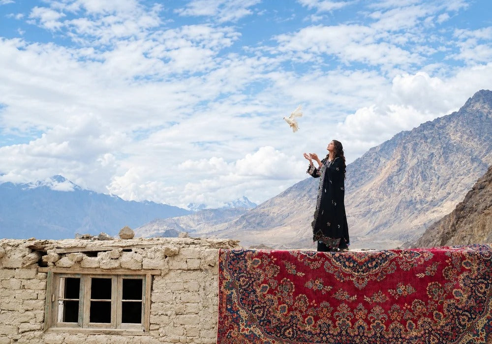 Woman in black embroidered outfit releasing a white dove in the northern mountains